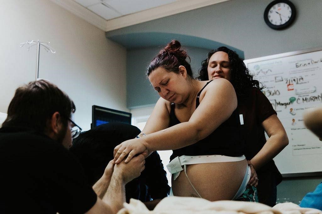 A birth doula provides pain and discomfort relief using pressure points and massage techniques to a laboring mother